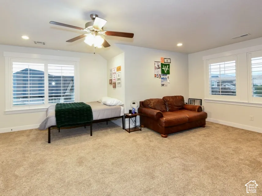 Carpeted room featuring multiple windows with louvered blinds, a ceiling fan with integrated lighting, and recessed ceiling lights