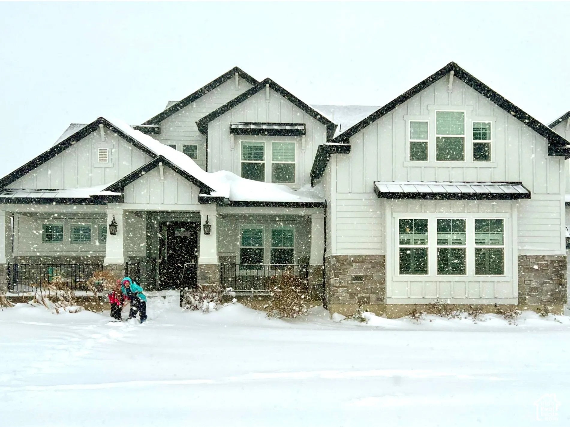 Modern farmhouse architectural style featuring white board and batten siding and stone accents