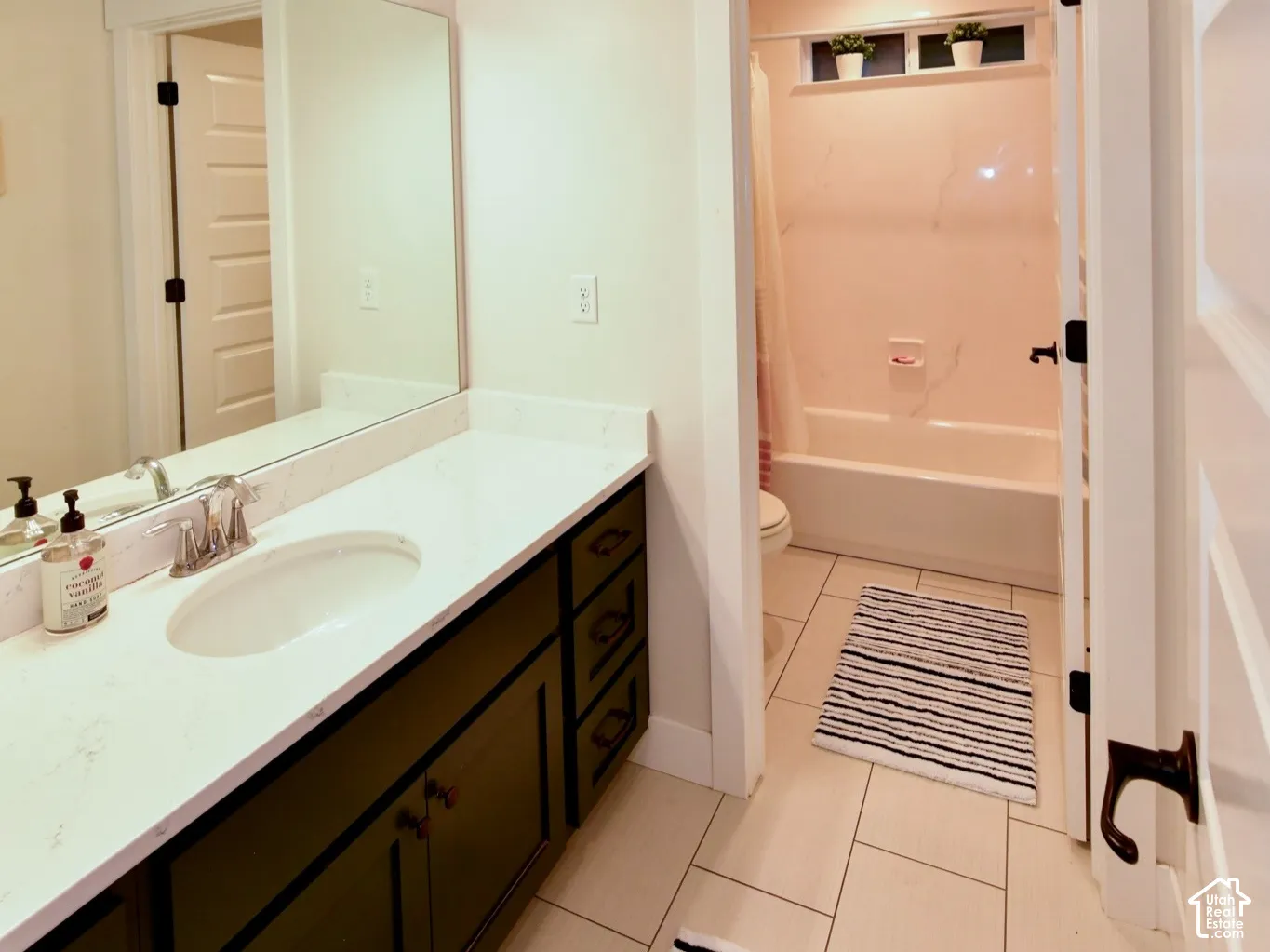 Bathroom featuring a vanity with a white countertop and dark cabinetry, a rectangular sink with chrome fixtures, and a large mirror