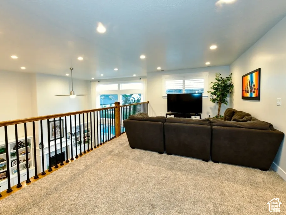 Carpeted loft area featuring a wood and metal railing, recessed lighting, and a ceiling fan