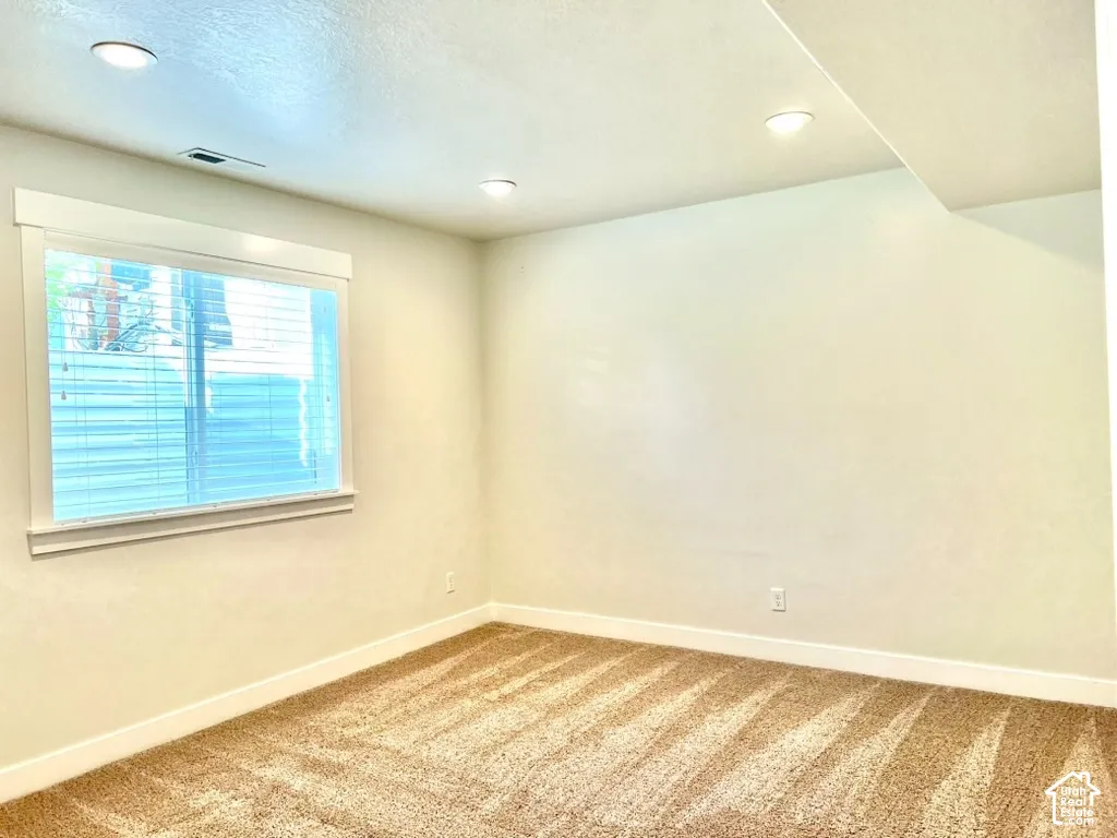 Room featuring recessed lighting, a window with horizontal blinds, neutral wall paint, and beige carpeting
