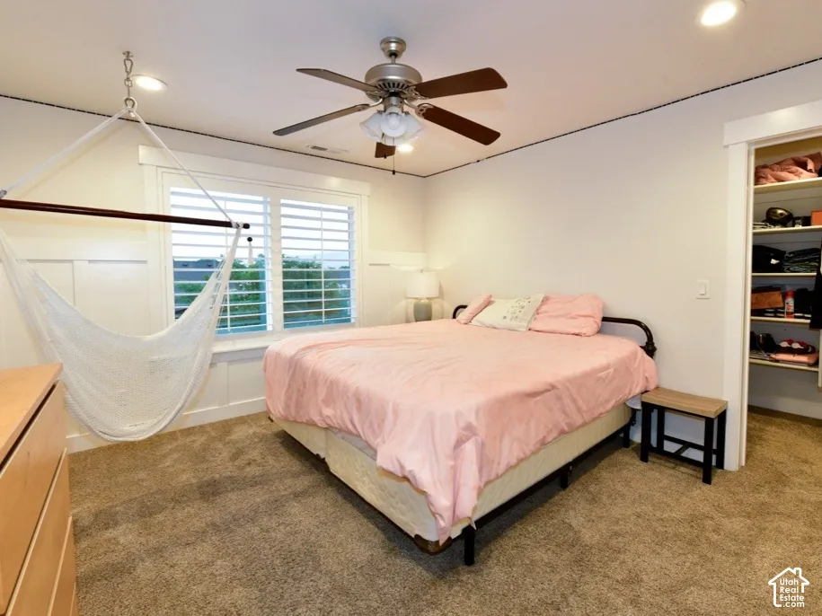 Carpeted room featuring a window with white plantation shutters, white wainscoting, and a ceiling fan with integrated lighting