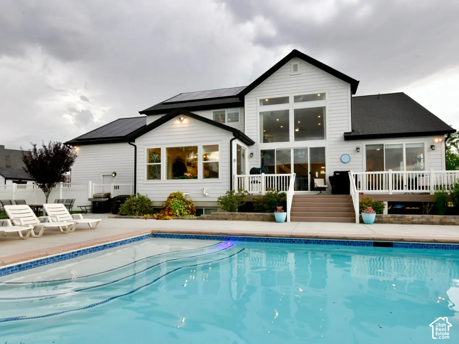 White siding home with a large backyard swimming pool featuring a curved entry