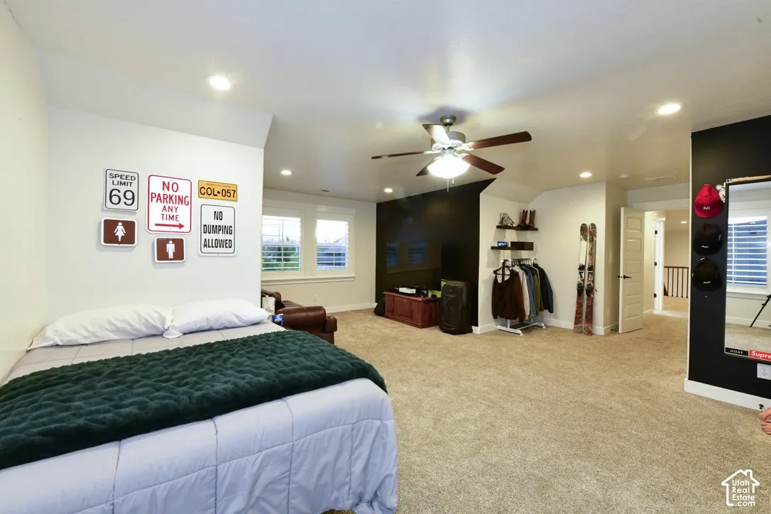 Spacious room featuring neutral carpet flooring, recessed lighting, ceiling fan, and multiple windows with white louvered blinds