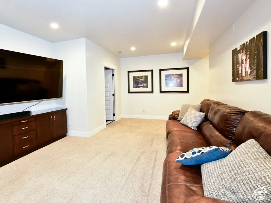 Recessed lighting illuminates a spacious room featuring wall-to-wall carpeting and a built-in media console with dark wood cabinetry and ample storage