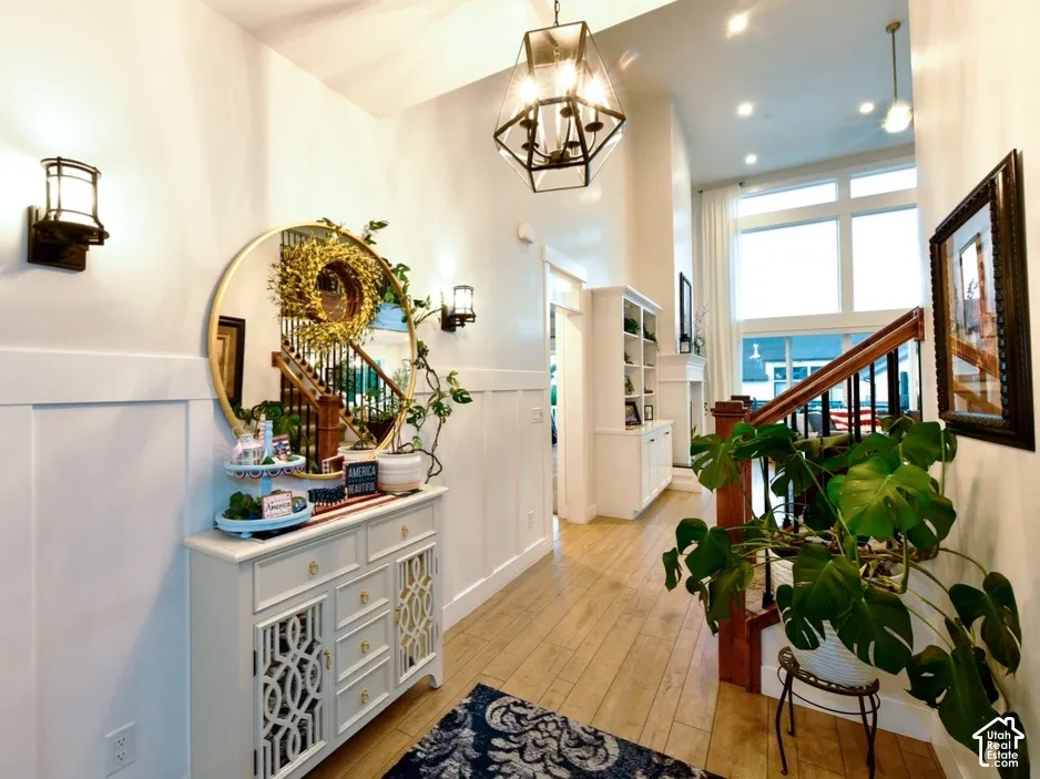 Two-story entryway featuring wood-finish flooring, wainscoting, and a prominent staircase with dark wood railing