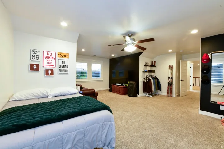 Spacious room featuring neutral carpet flooring, recessed lighting, ceiling fan, and multiple windows with white louvered blinds