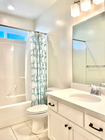 Bathroom featuring a white vanity with a light-toned countertop, a rectangular mirror, and a three-light fixture