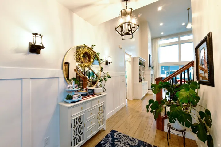 Two-story entryway featuring wood-finish flooring, wainscoting, and a prominent staircase with dark wood railing
