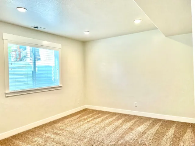 Room featuring recessed lighting, a window with horizontal blinds, neutral wall paint, and beige carpeting