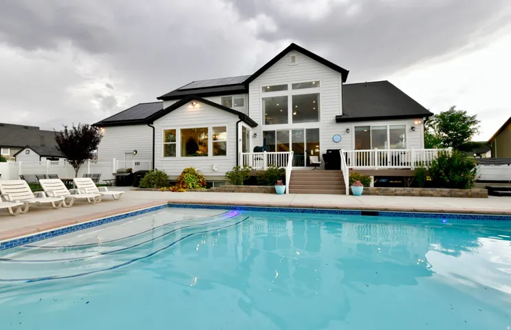 White siding home with a large backyard swimming pool featuring a curved entry