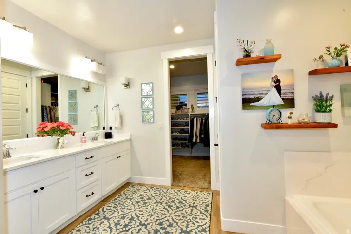 Bright bathroom featuring a double vanity with white cabinetry, dual undermount sinks, and a light-toned countertop