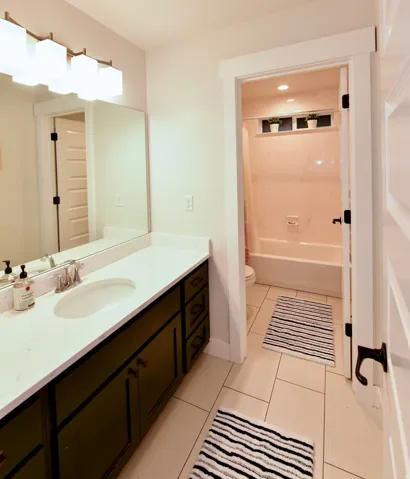 Bathroom featuring a vanity with a white countertop and dark cabinetry, a rectangular sink with chrome fixtures, and a large mirror