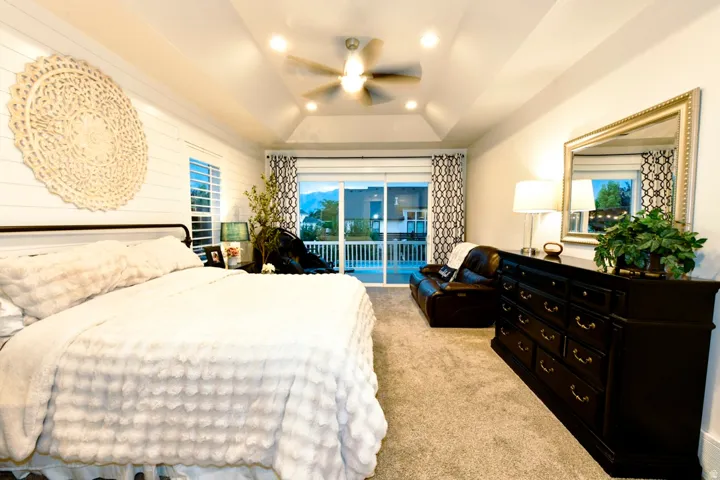 Spacious bedroom featuring a tray ceiling with recessed lighting and a ceiling fan