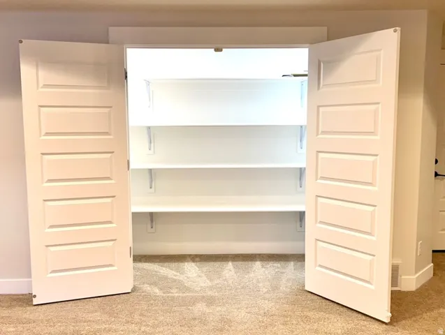 Double panel doors opening to a built-in closet with three shelving units