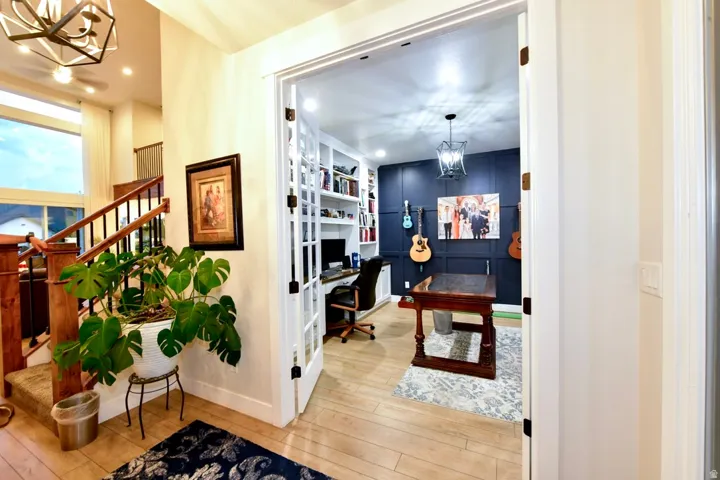 Office space featuring French doors, built-in shelving, wood-finish flooring, and a decorative paneled accent wall