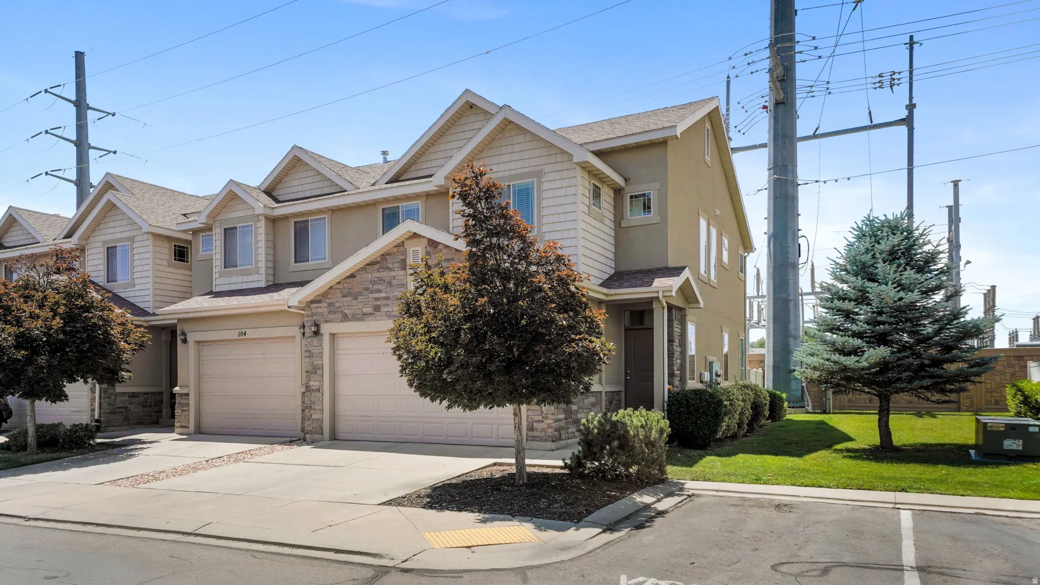 Multi-level townhome featuring a stucco and stone facade, dormer windows, and attached two-car garage