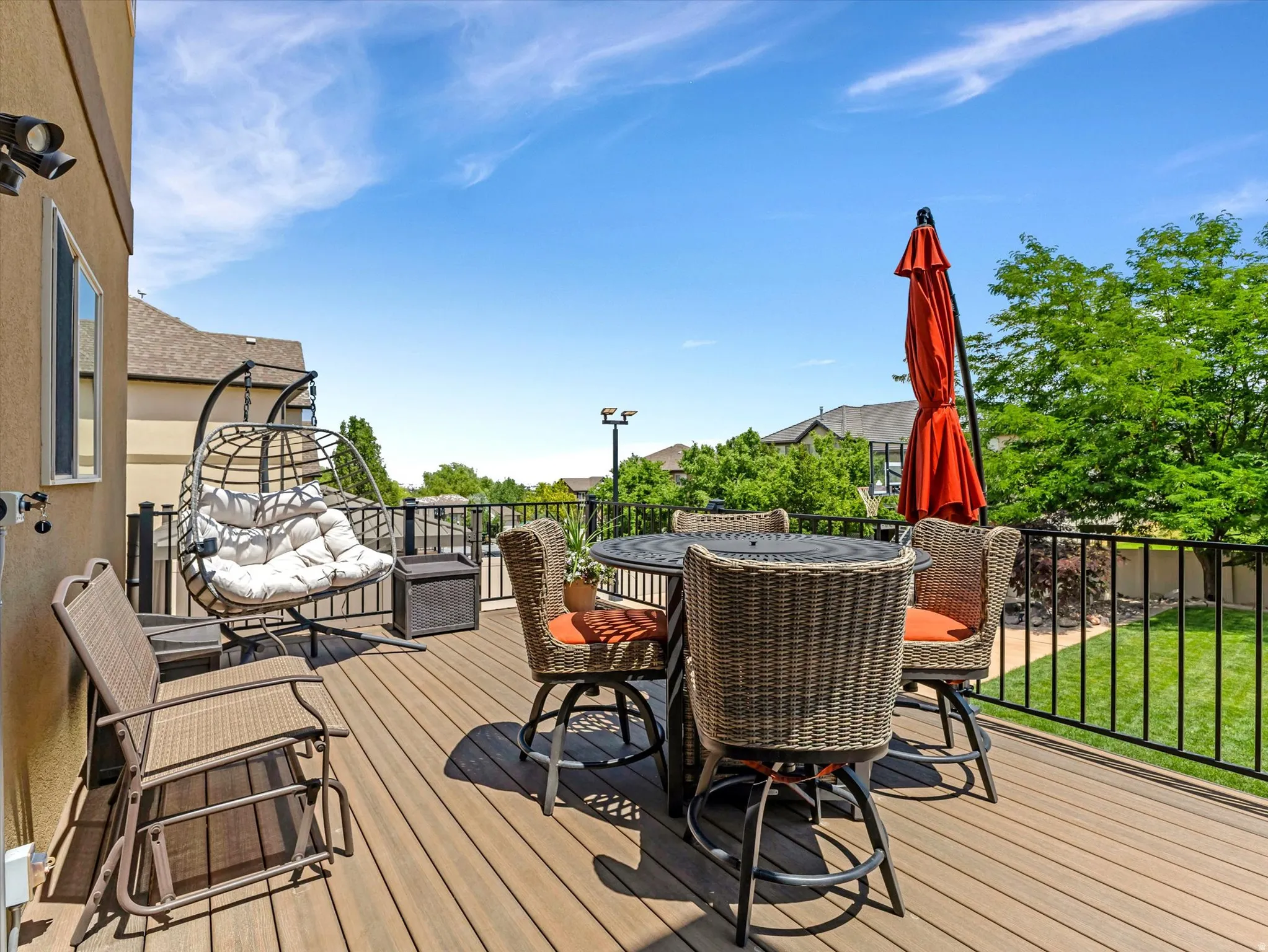 Spacious outdoor deck featuring wood-finish flooring, black metal railings, and a stucco exterior wall