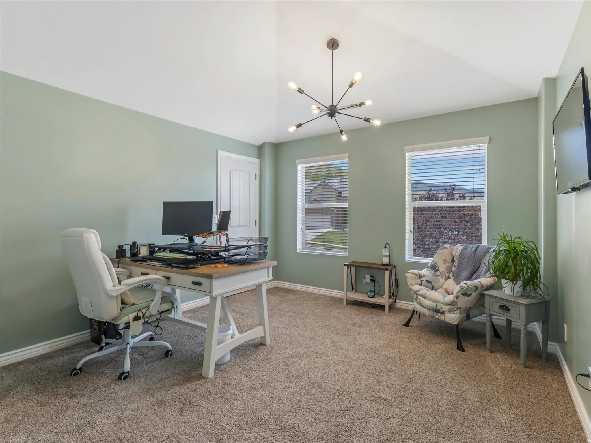 Spacious room featuring vaulted ceilings, a contemporary sputnik-style light fixture, two windows with blinds, and light green walls with white trim