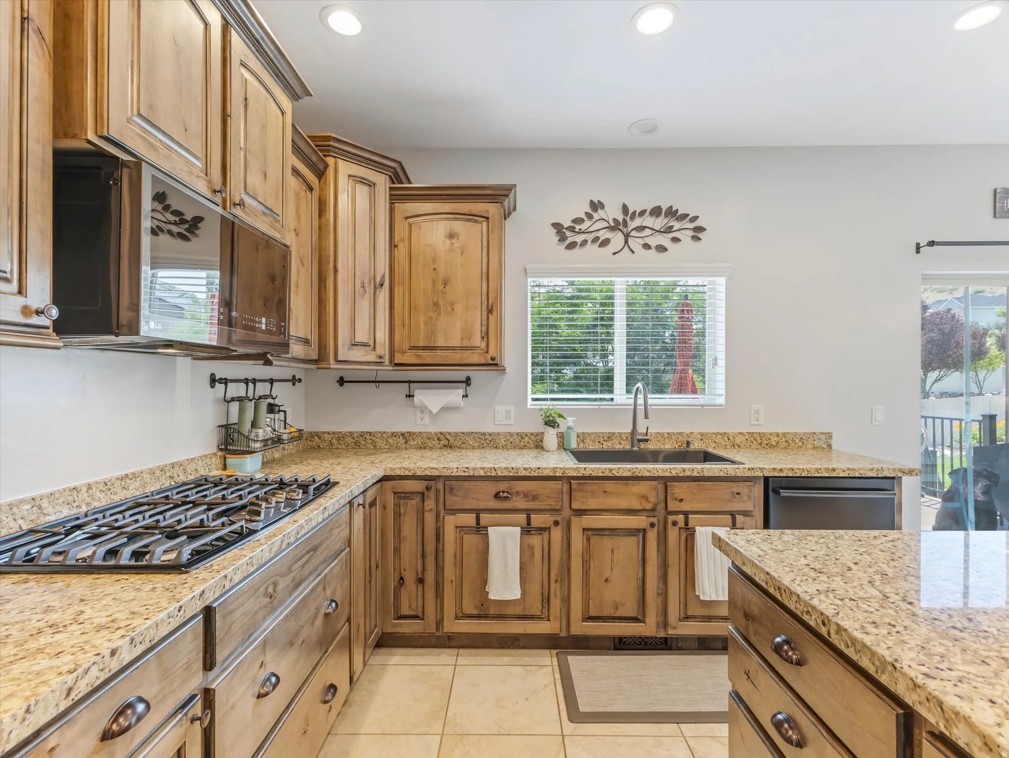 Kitchen featuring wood cabinetry, granite countertops, tile flooring, a gas range, and a built-in microwave