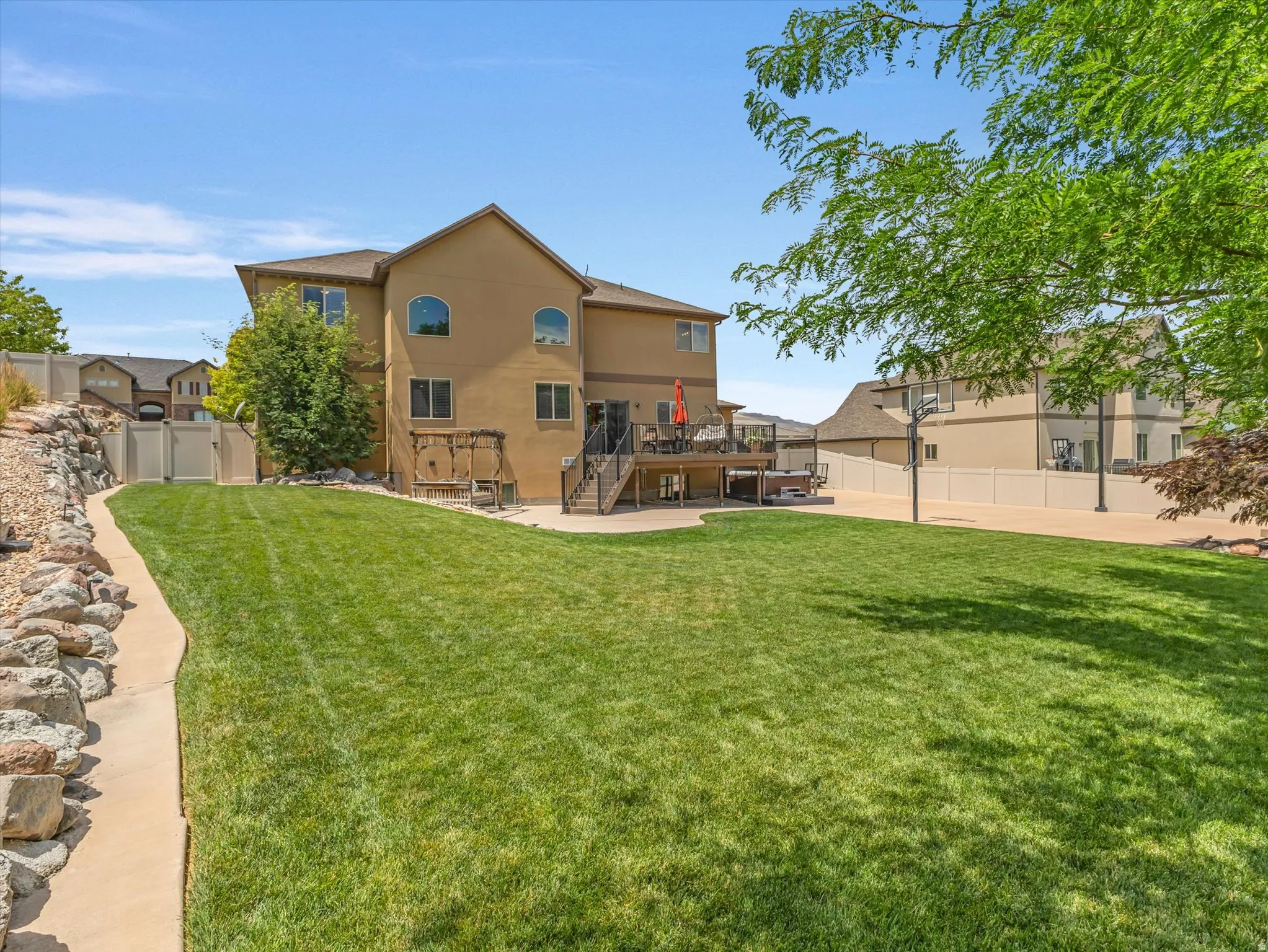 Expansive green lawn with a concrete pathway and stone retaining wall