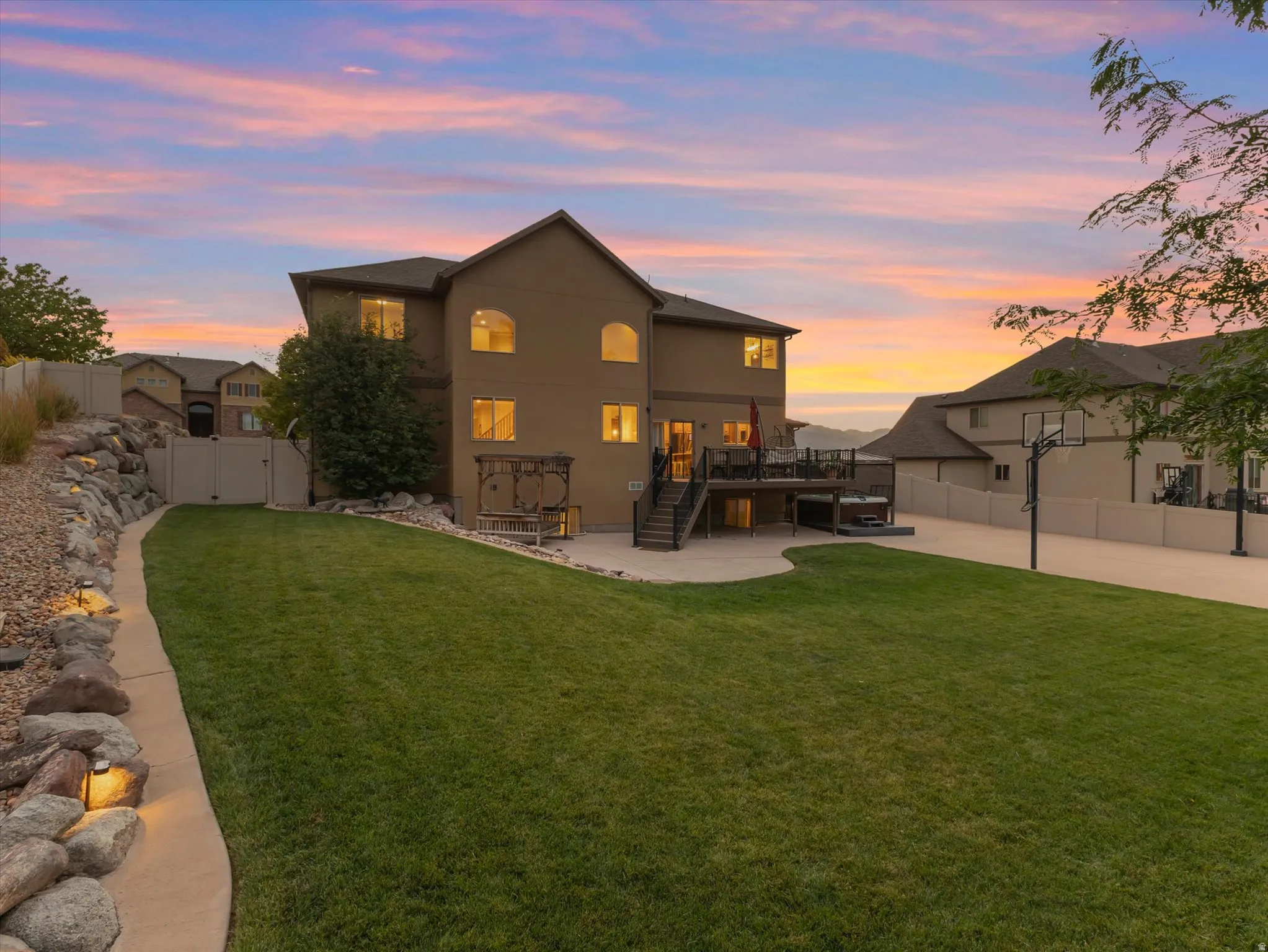 Rear exterior featuring an expansive lawn, multi-level deck, and concrete patio