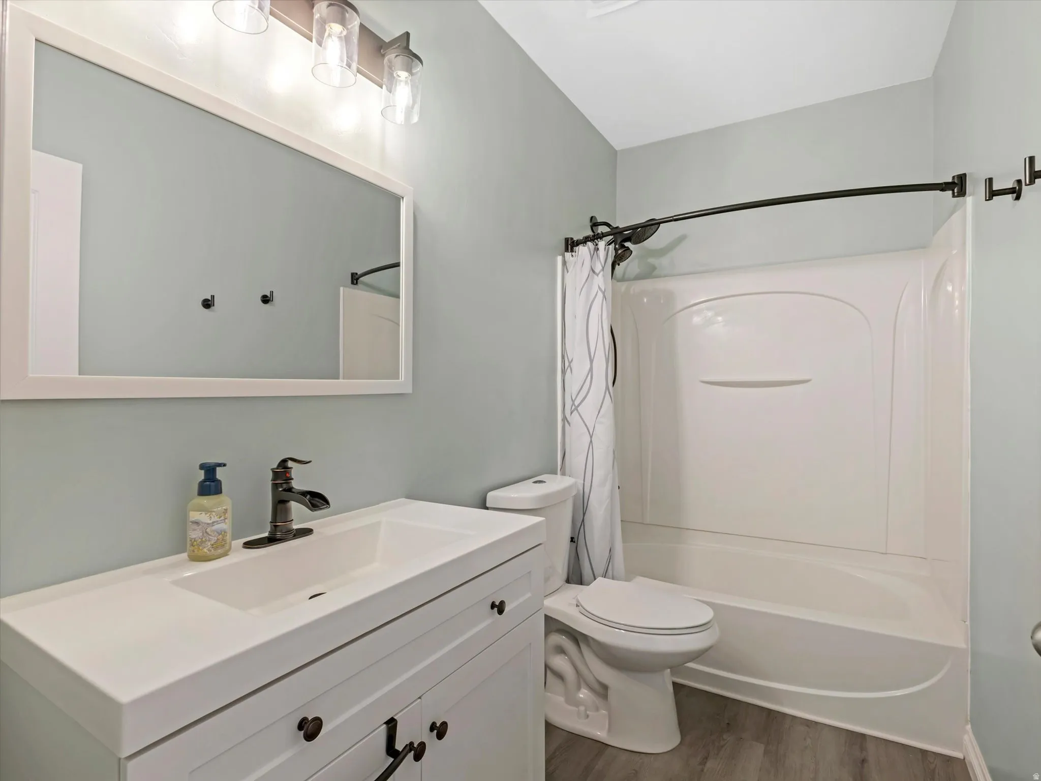 Bathroom featuring a white vanity with integrated sink, bronze-finish faucet, and coordinating bronze-finish light fixture