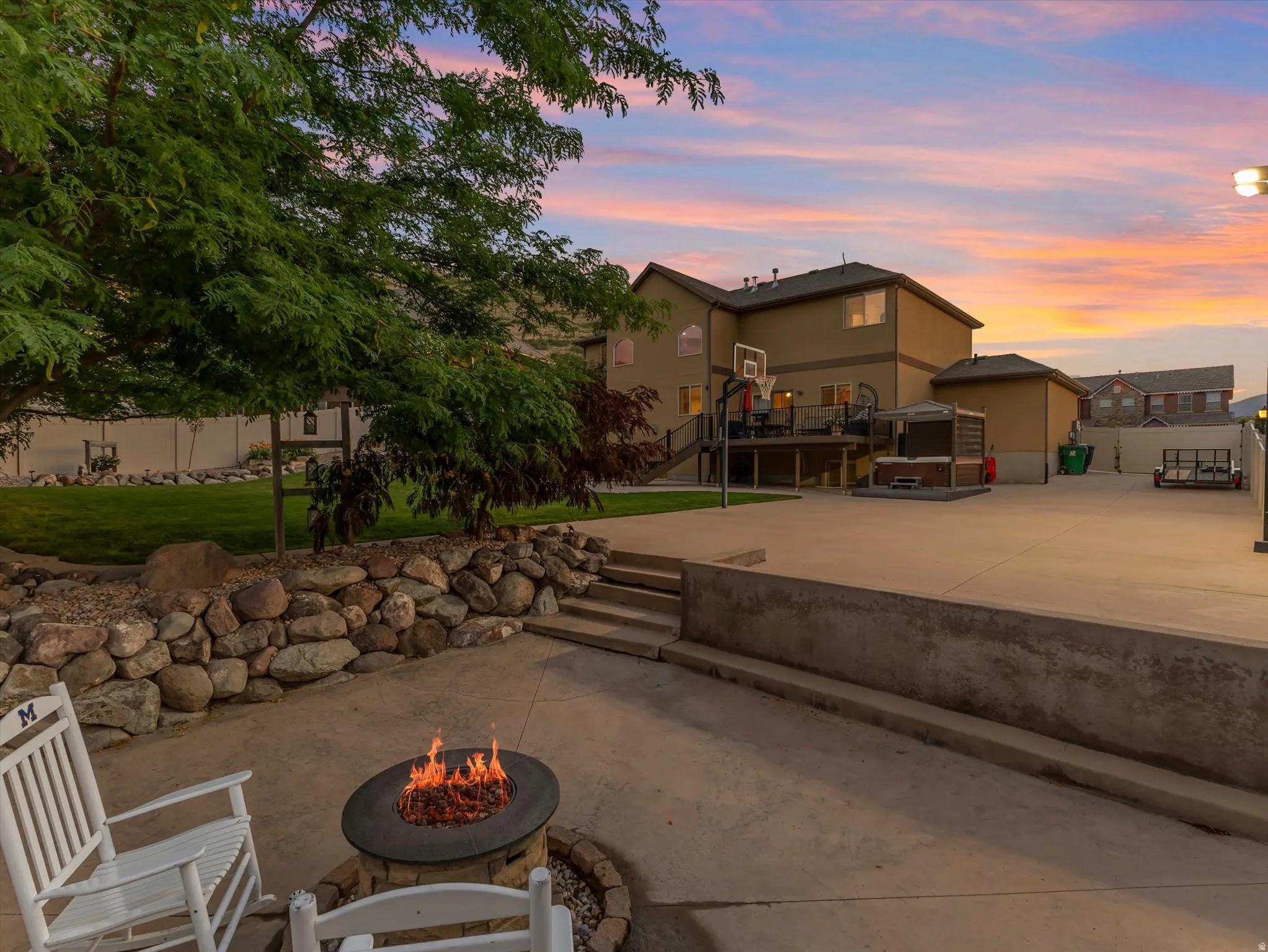 Backyard patio featuring a built-in fire pit, concrete hardscaping, and a stacked stone retaining wall