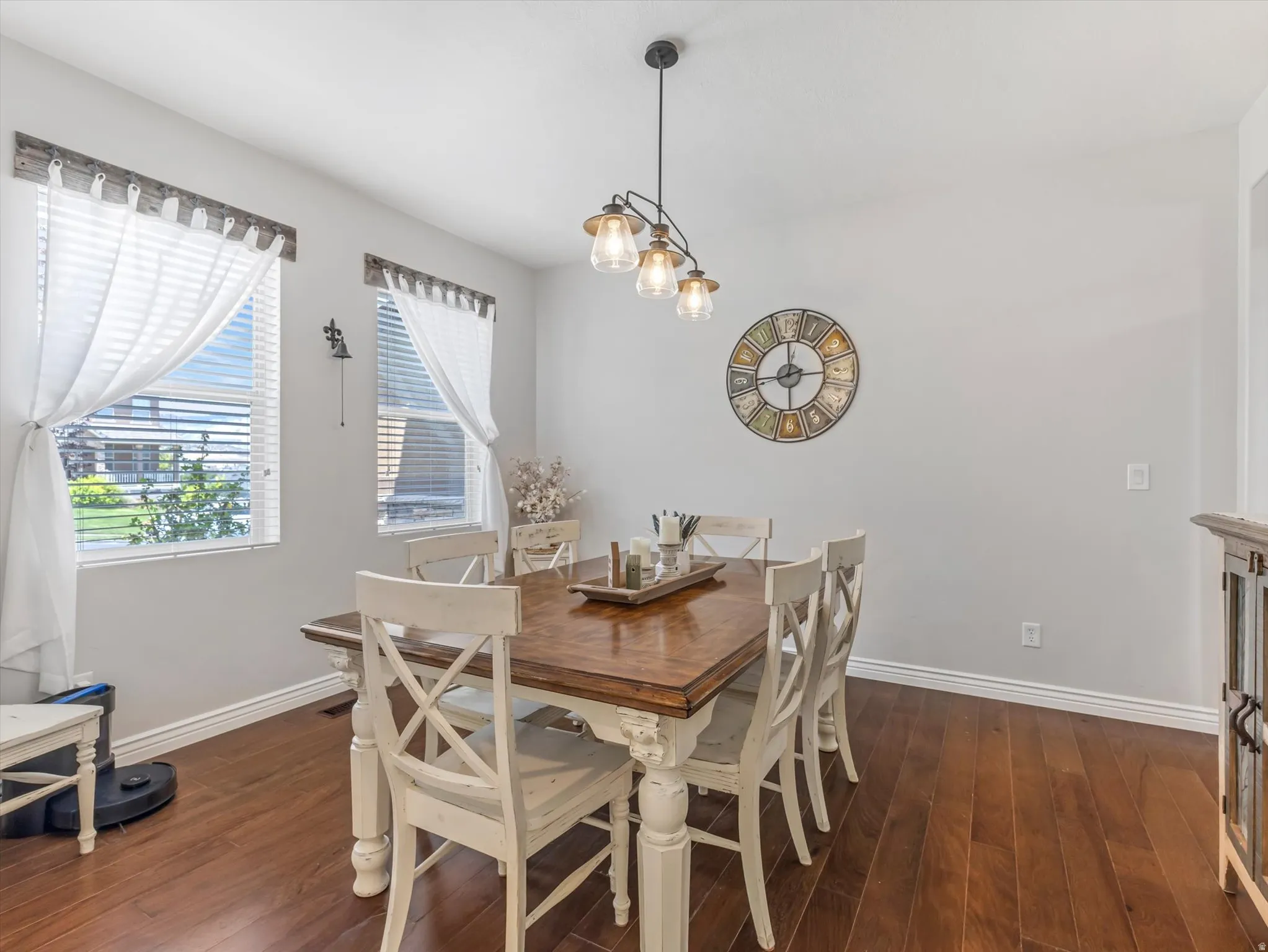 Dining area featuring wood-finish flooring, two large windows, and a multi-light pendant fixture