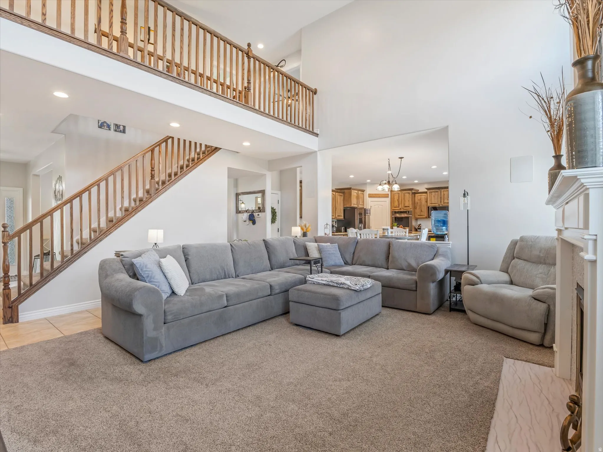 Open-concept living space featuring a two-story ceiling, a staircase with wood railings, and an upper-level balcony