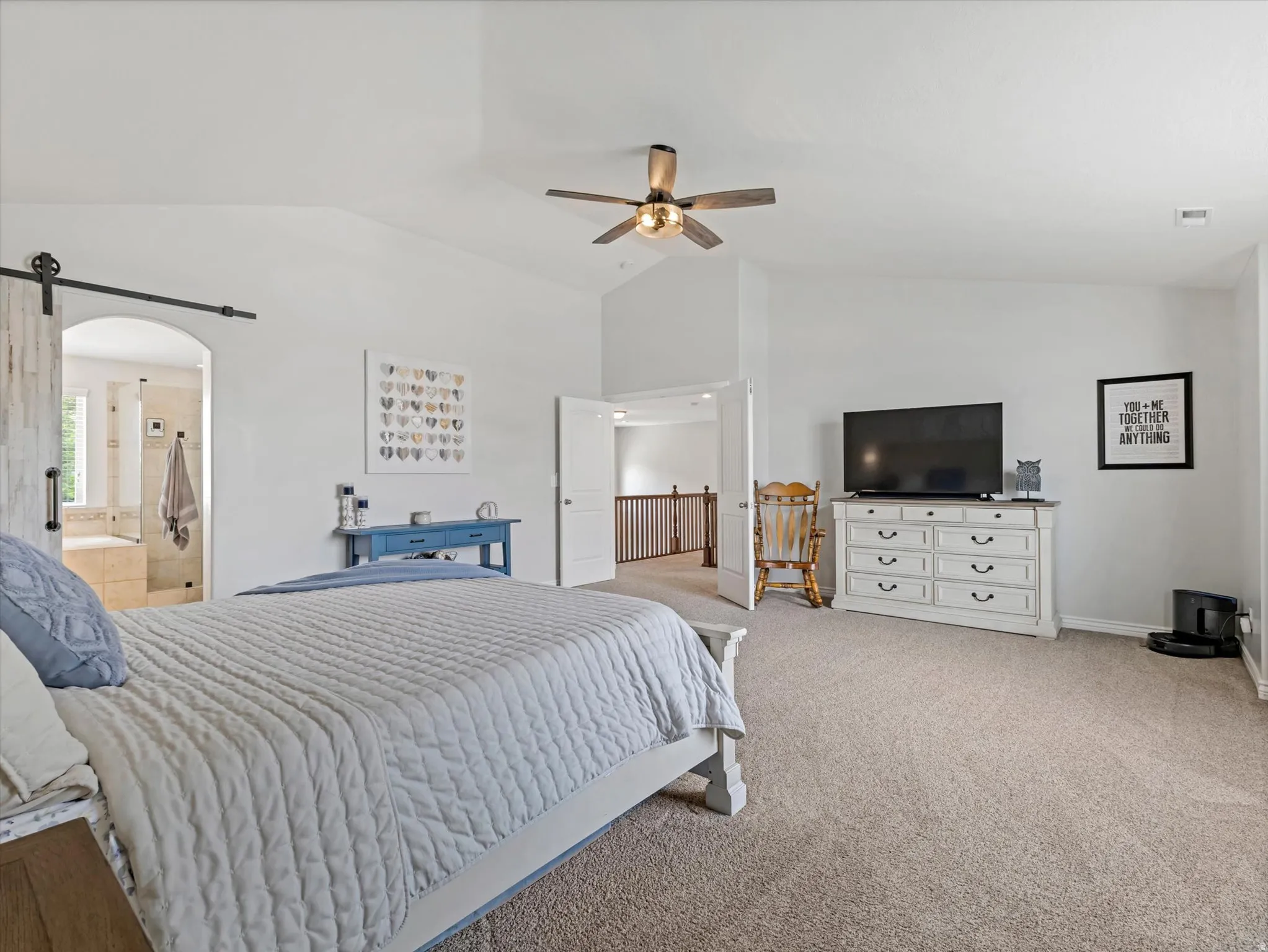 Spacious carpeted bedroom with vaulted ceilings and a ceiling fan