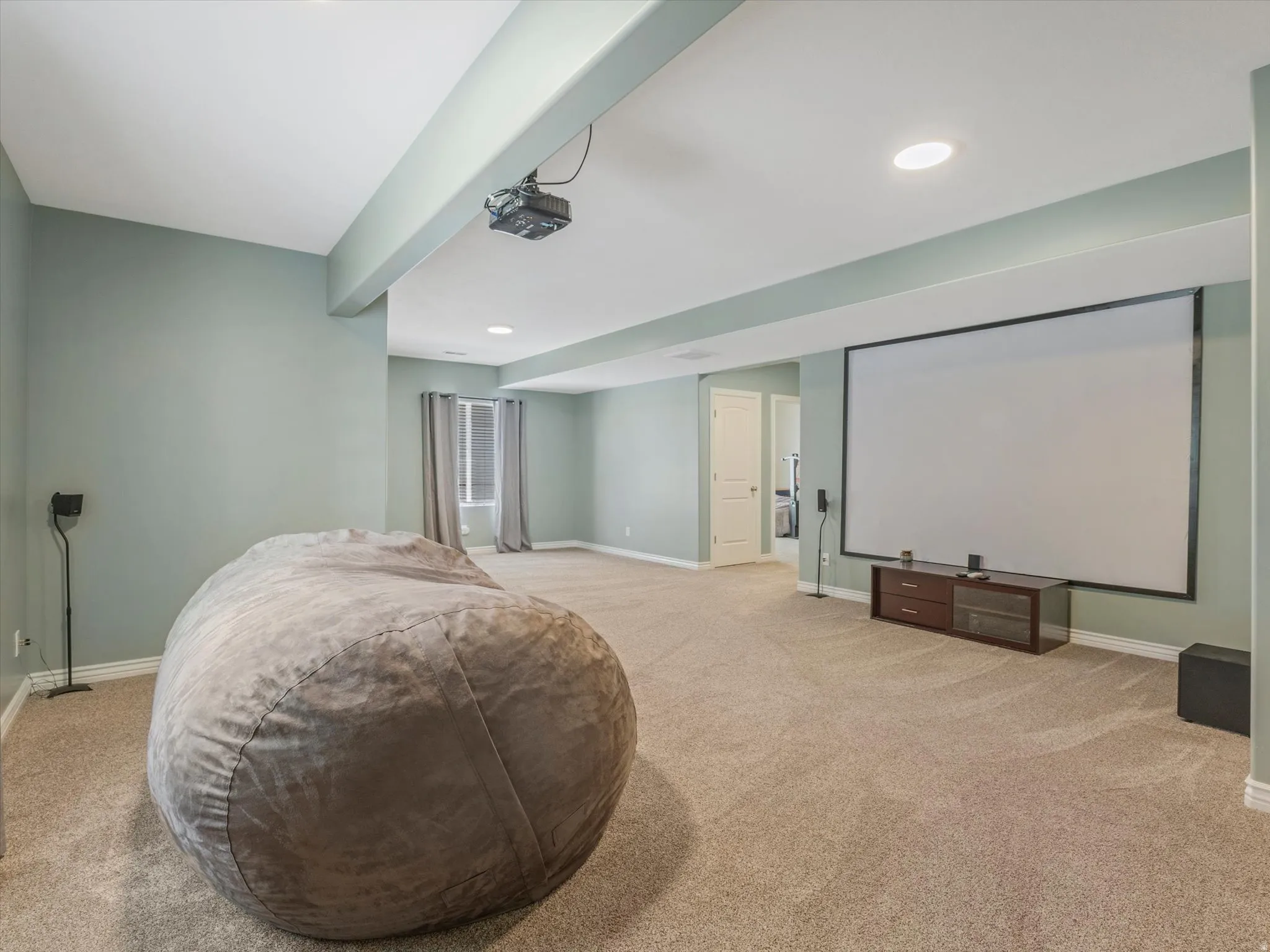 Spacious room featuring neutral carpet flooring and light green walls