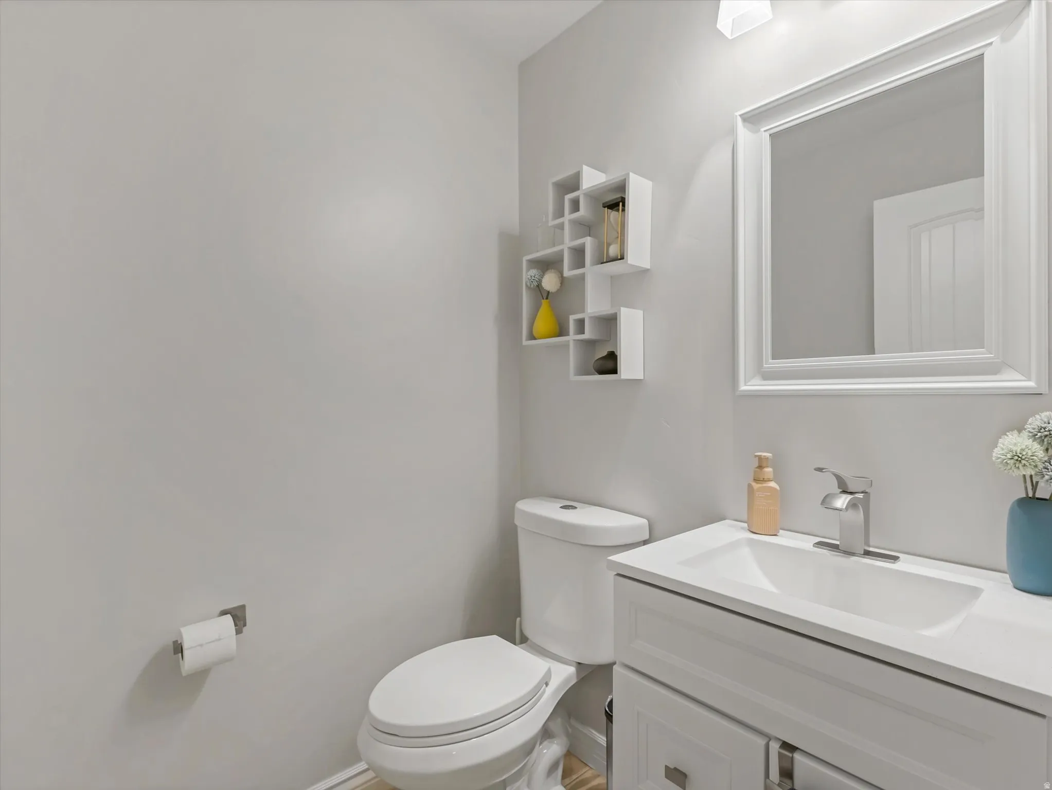 Bathroom featuring a white vanity with an integrated sink, polished chrome faucet, and a framed mirror