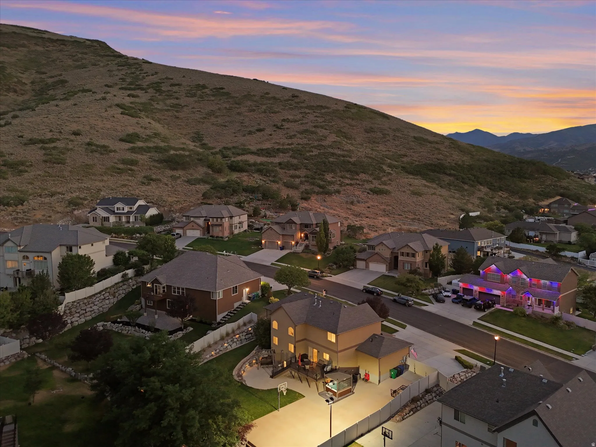 Residential neighborhood with diverse home styles, set against a brush-covered hillside