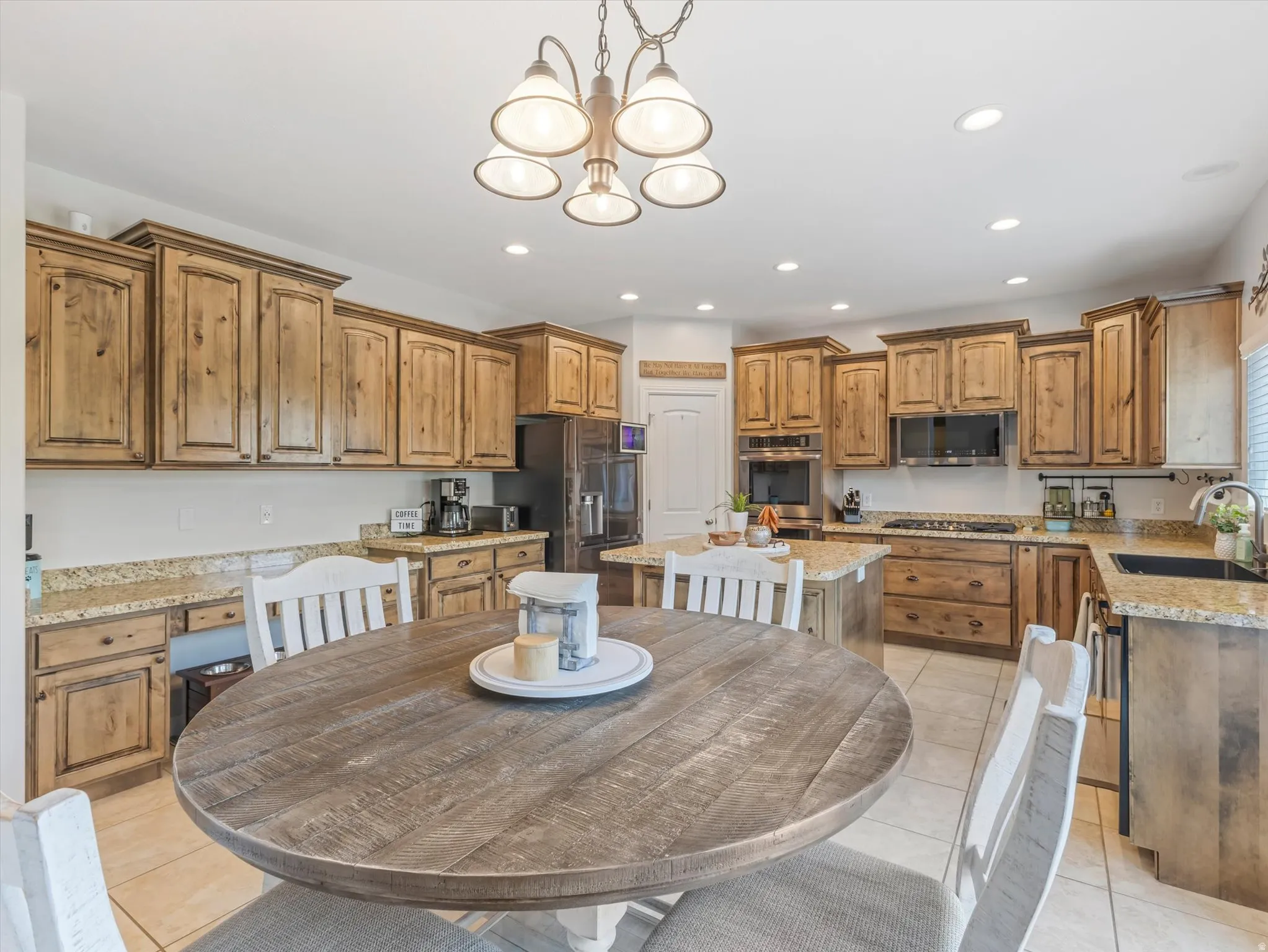 Expansive kitchen featuring light wood cabinetry, stone countertops, a central island, stainless steel appliances, and recessed lighting