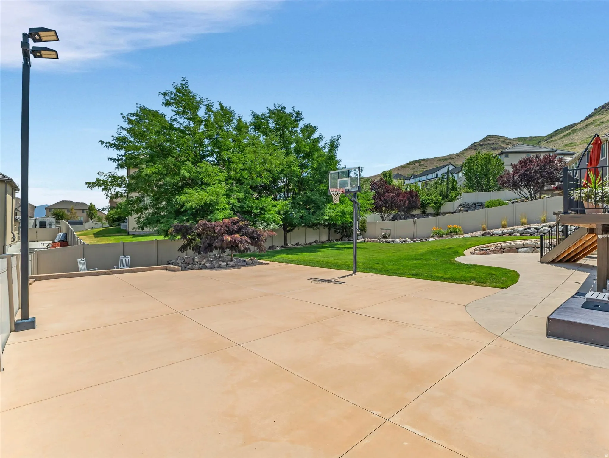 Expansive concrete patio area featuring a basketball hoop