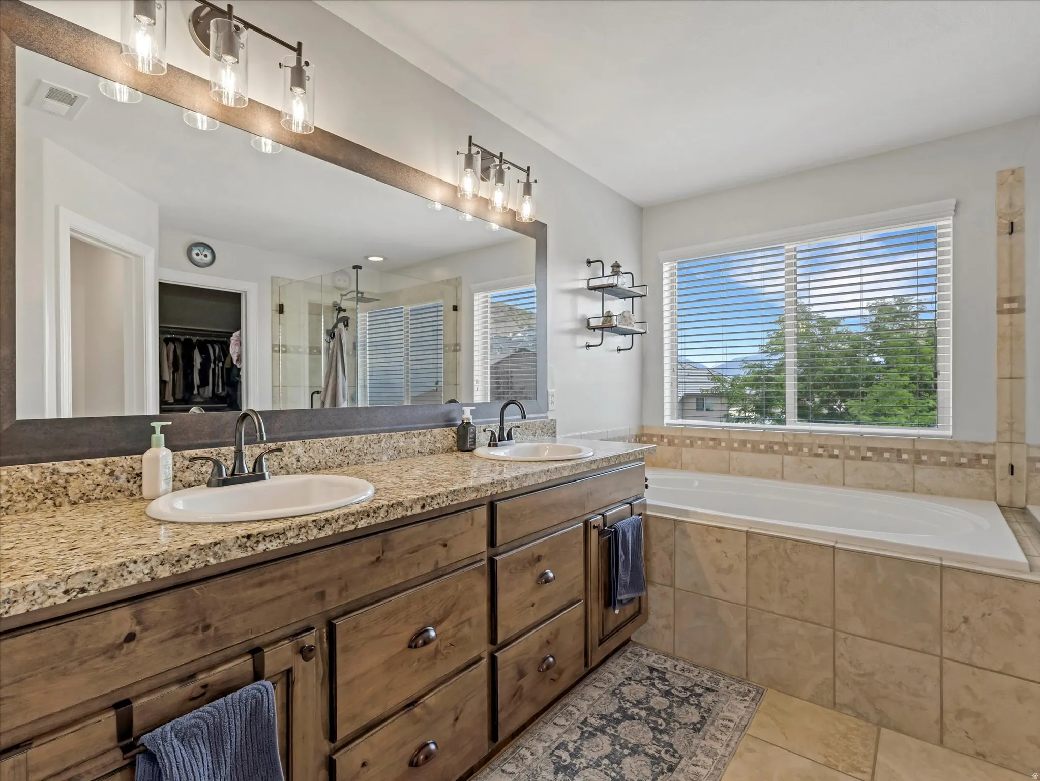 Dual vanity with granite-style countertop, undermount sinks, and dark wood cabinetry