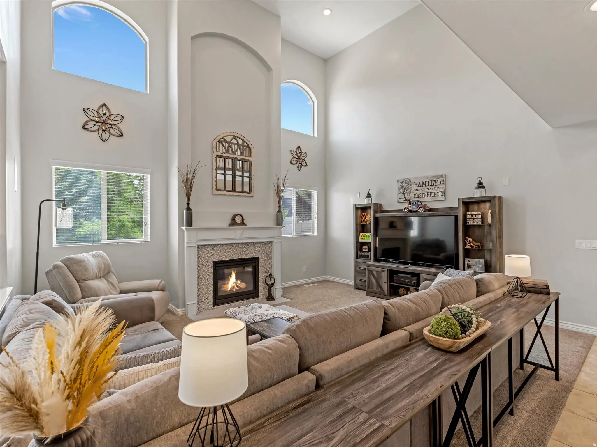 Vaulted ceilings featuring arched windows and a fireplace with tile surround