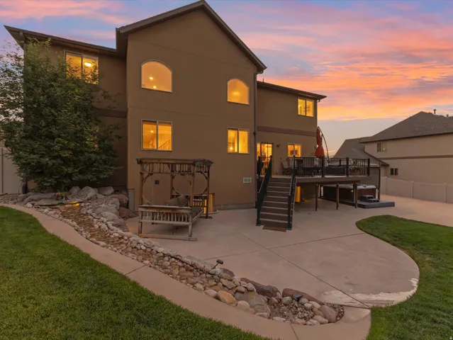 Rear exterior featuring a multi-level deck with black railings, a spa, and concrete patio