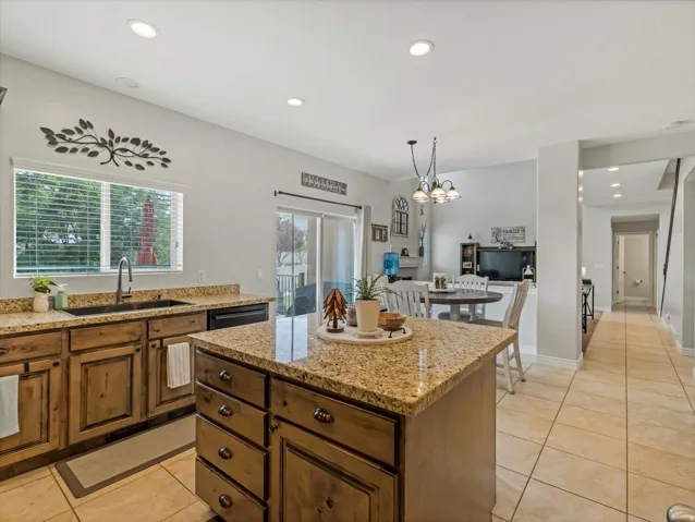 Kitchen featuring wood-finish cabinetry, granite countertops, and a central island