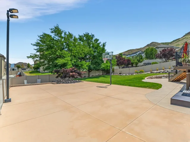 Expansive concrete patio area featuring a basketball hoop