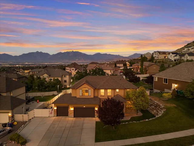 Elevated property featuring a two-story residence with a two-car garage and a stone facade accent