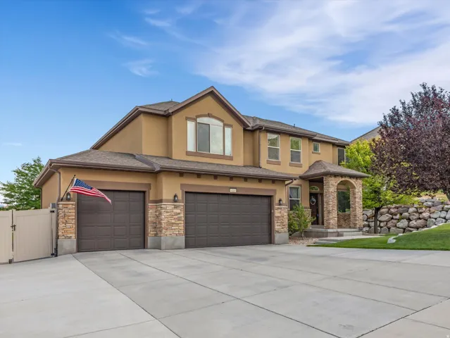 Two-story stucco exterior featuring stone accents, a covered entry, and a multi-car garage