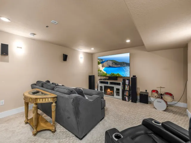 Dedicated entertainment space featuring recessed lighting, wall-mounted speakers, and a large display above a white media console with a built-in electric fireplace