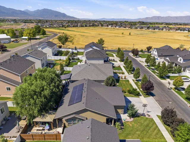 Neighborhood aerial showcasing residential properties with dark shingle roofing, solar panel installations, and established landscaping