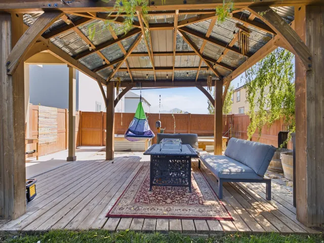 Outdoor gazebo featuring a metal roof, wood-plank flooring, and sturdy wood beams