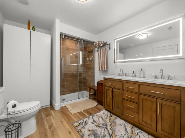 Contemporary bathroom featuring a spacious dual-sink vanity with wood cabinetry and a large illuminated mirror