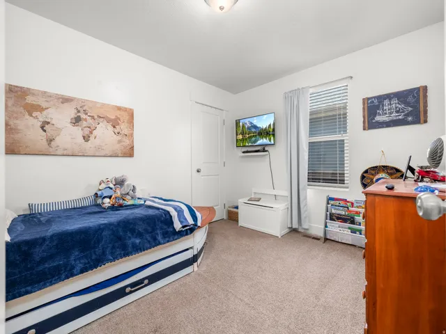 Bedroom featuring light neutral wall paint, a window with horizontal blinds, neutral carpet flooring, and a white ceiling with a flush-mount light fixture