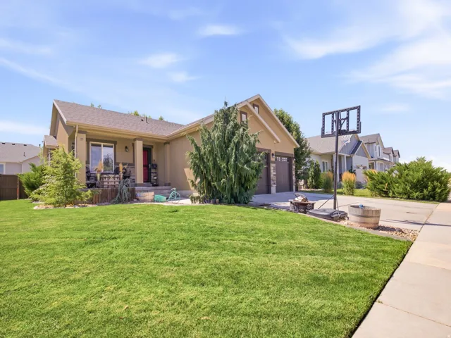 Landscaped front yard featuring a verdant lawn, mature trees, and a concrete driveway
