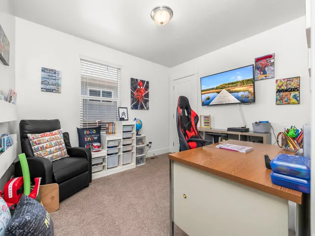 Carpeted room featuring a ceiling-mounted light fixture, a window with horizontal blinds, and a built-in wall shelf